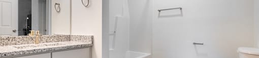 A white bathroom with a toilet, sink, and shower.
