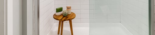 a white bathroom with a shower and a small wooden table