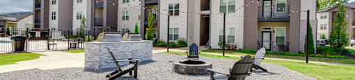 an outdoor area with a fire pit and chairs in front of an apartment building