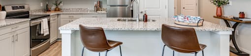 an open kitchen with a large island with two bar stools