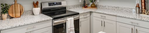 a kitchen with white cabinets and a stove and microwave