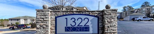 A sign with for 1322 North Apartments is surrounded by flowers in Auburn, AL.