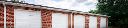 A red brick building with four white garage doors.