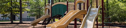 A playground with a yellow slide and a green roofed structure.
