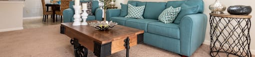 A living room with a blue couch and a painting on the wall.