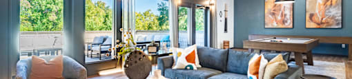a living room with a blue couch and a table    and large windows