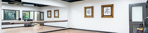 an empty dance studio with a hardwood floor and white walls