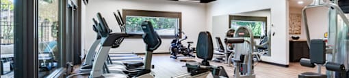 a gym with treadmills and other exercise equipment on a wooden floor