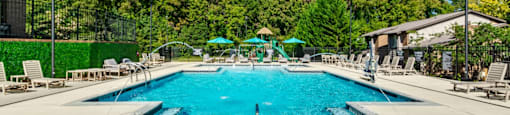a swimming pool with chairs and umbrellas at the resort on a sunny day