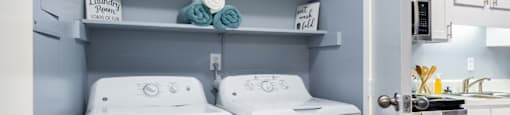 a white washer and dryer in a small laundry room with shelves
