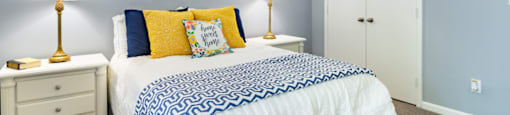 a blue and white bedroom with a bed and blue and yellow pillows