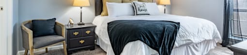 a bedroom with a bed and a chair and a window
