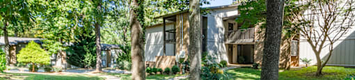 a sidewalk in front of a house with trees