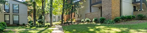 a sidewalk in front of a building with grass and trees