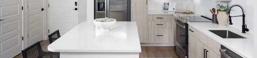A modern kitchen with a white island and wooden floors.
