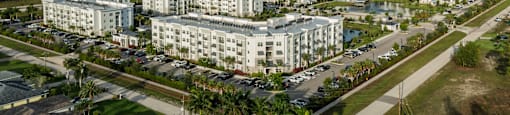 A large white building complex with a parking lot in front of it.