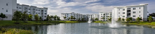 A serene lake surrounded by buildings with a fountain in the middle.