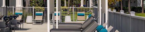 A row of sun loungers are on a wooden deck.