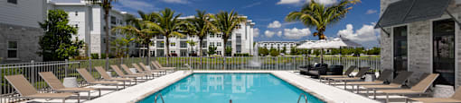 A large swimming pool surrounded by lounge chairs and palm trees.