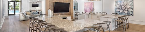 A large dining table with chairs is in the middle of a spacious room with a television and a fireplace.