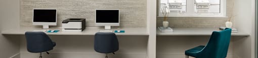 Two computers on a desk with a blue chair.