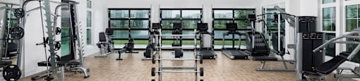 A gym with a variety of equipment including treadmills, weights, and exercise machines.