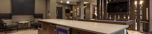 A modern kitchen with a long island and a TV mounted on the wall.