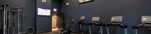 A gym with treadmills, weights, and a television.