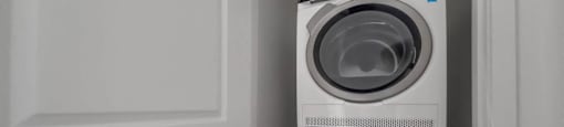 A white washing machine is stacked on top of another in a small space.