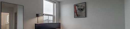 A bedroom with a bed, a table, and a mirror.