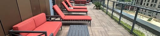 a row of red lounge chairs on a balcony in a skyscraper