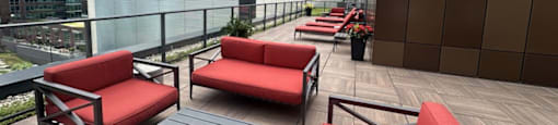 a terrace with red couches and tables on a balcony with skyscrapers