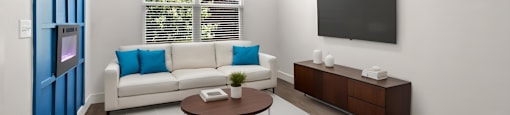 State Street Flats 1 bedroom apartments Nashville modern living room with a white couch, a brown coffee table, an electric fireplace, and a flat-screen TV mounted on the wall.