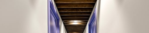 State Street Flats one bedroom apartments Nashville long hallway with blue doors and a wooden ceiling.