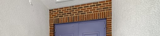 State Street Flats in Nashville blue door is in a room with a brick wall.