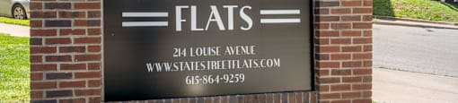 A sign for State Street Flats is displayed in front of a building.