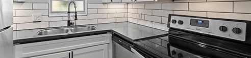 A modern kitchen with white cabinets and a black countertop at Watermarc one and two bedroom apartments in Lakeland, FL.