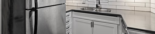 A modern kitchen with white cabinets and a black countertop at Watermarc one and two bedroom apartments in Lakeland, FL.