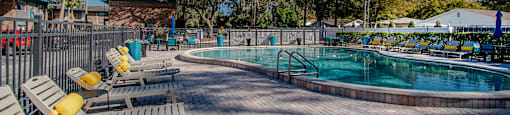 A large outdoor swimming pool surrounded by trees at Watermarc Apartments Lakeland, FL