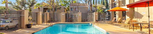 A swimming pool surrounded by a fence and palm trees.
