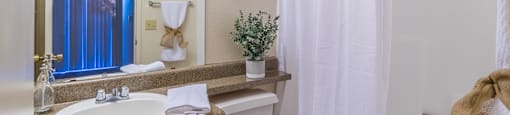 Bathroom with large mirror and white curtains covering tub and shower