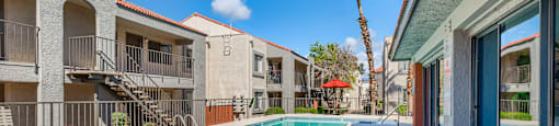A pool area with a table and chairs and a building in the background.