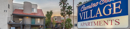 Blue and white lit sign on top of bricks, buildings in background