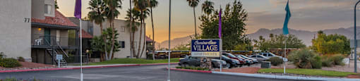front entrance of apartment complex with sign and flags