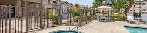 A small pool with a slide in the middle of a concrete patio.