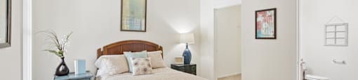 A bedroom with a bed, nightstand, and a painting on the wall.