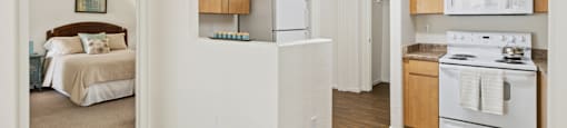 A white kitchen with wooden cabinets and a white stove top oven.