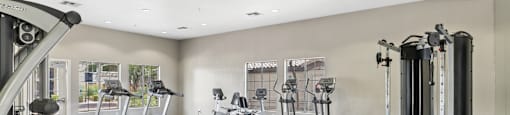 A gym with a variety of equipment including treadmills, weights, and benches.