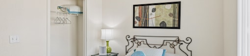 A bedroom with a bed, nightstand, and a painting on the wall.