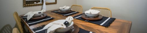 A dining room with a wooden table set for two.